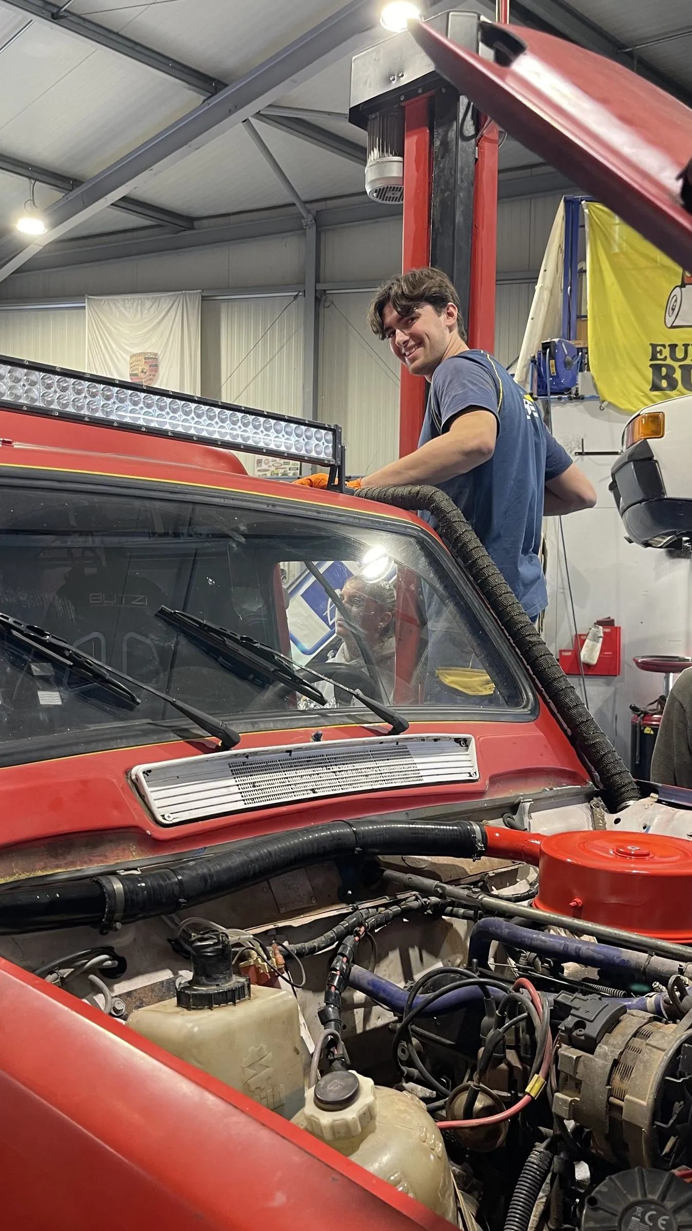 Un membre de l'équipe sourit en travaillant sous le capot de la 4L.