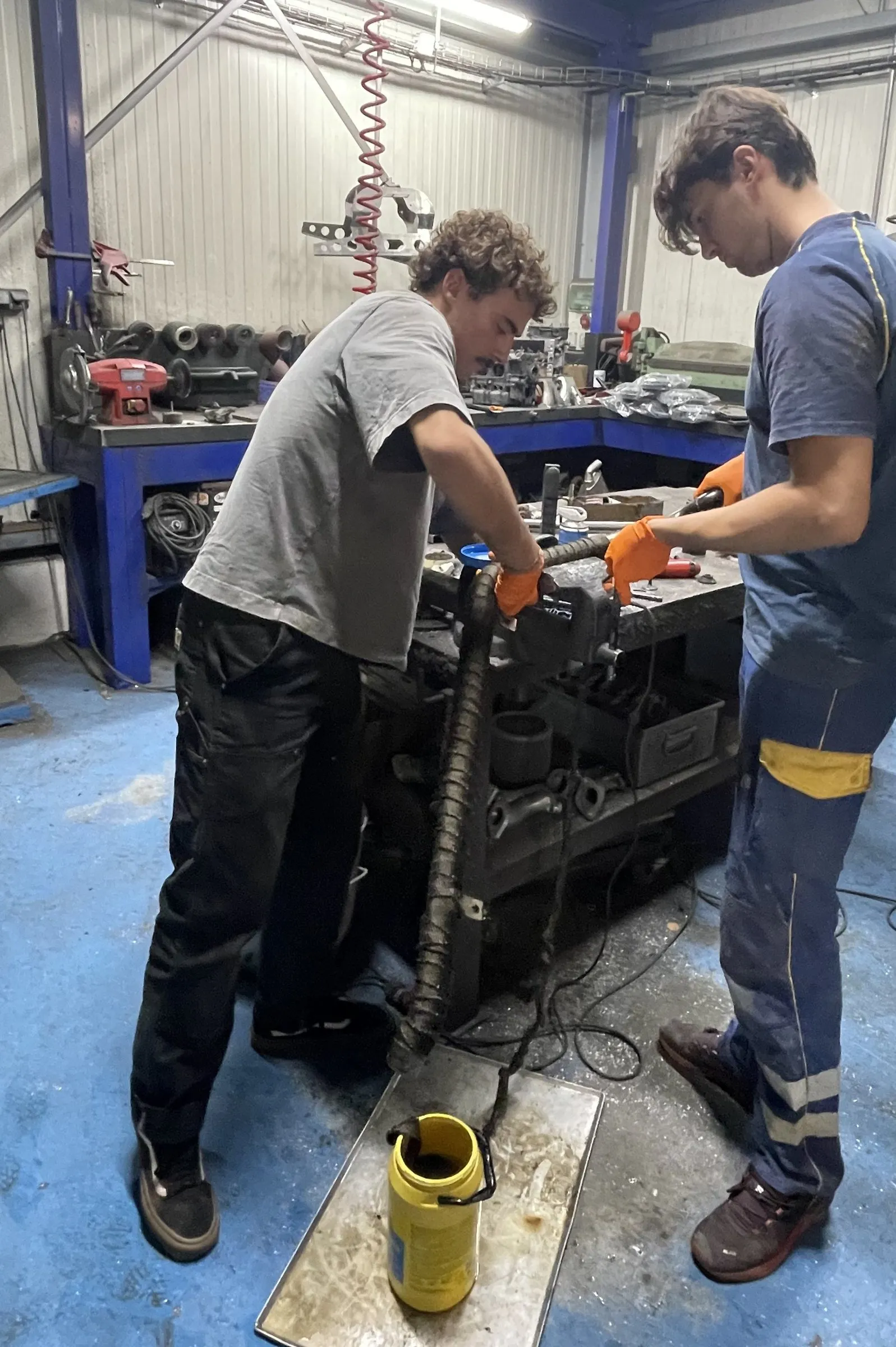 Deux membres de l'équipe travaillent sur une pièce à l'établi de l'atelier.
